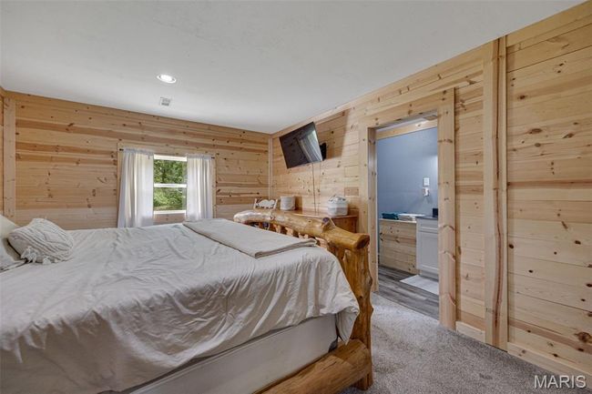 Bedroom featuring wooden walls, carpet, recessed lighting, and ensuite bath | Image 9