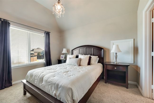 Bedroom featuring light colored carpet, lofted ceiling, and a chandelier | Image 23