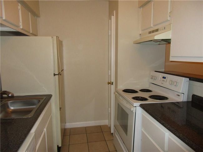 Kitchen featuring sink, white appliances, light tile patterned floors, and white cabinets | Image 7