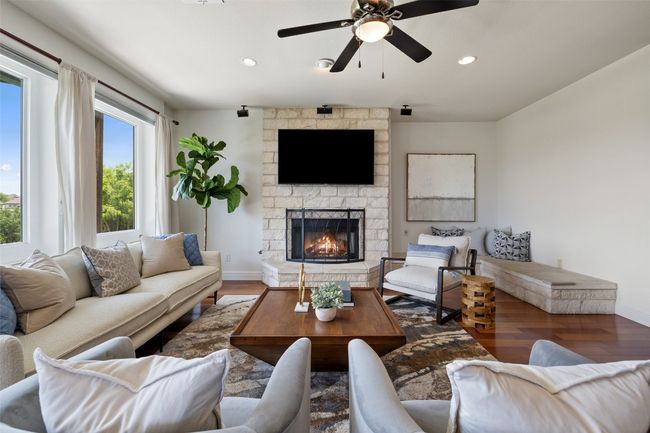 Living area with wood finished floors, recessed lighting, a stone fireplace, and a ceiling fan | Image 12