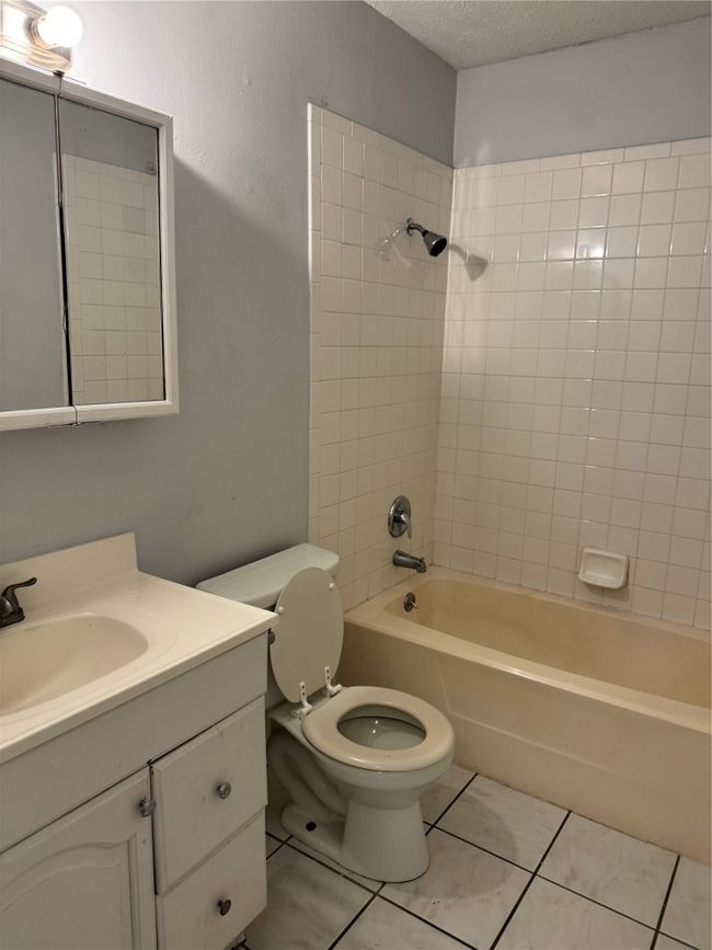 Full bathroom with a textured ceiling, tub / shower combination, vanity, and light tile patterned floors | Image 9