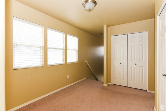 Unfurnished bedroom with baseboards, a closet, and light colored carpet | Image 27