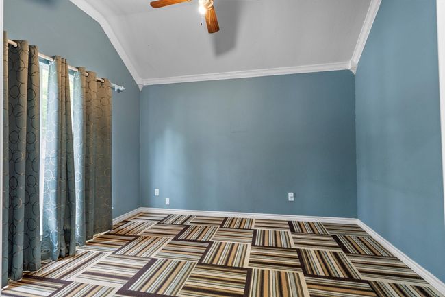 Unfurnished room with a ceiling fan, lofted ceiling, carpet, and crown molding | Image 6