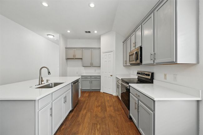 Kitchen with appliances with stainless steel finishes, gray cabinets, a sink, dark wood finished floors, and recessed lighting | Image 14