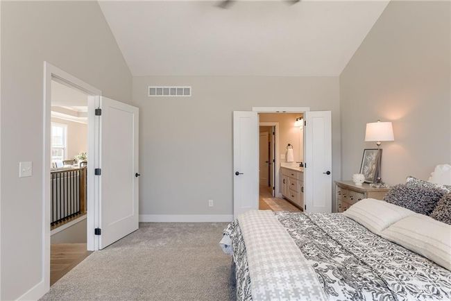 Bedroom featuring light carpet, visible vents, baseboards, and lofted ceiling | Image 17