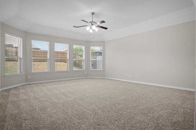 Carpeted empty room featuring baseboards, ceiling fan, visible vents, and a tray ceiling | Image 13