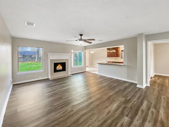 Spacious living room with two large windows, open to the kitchen and breakfast area. | Image 6
