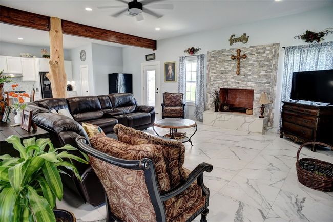 Flooring in first floor is porcelain tile. Living room featuring beamed ceiling, fireplace and recessed lighting | Image 12