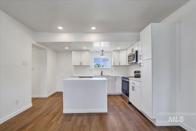 Kitchen featuring appliances with stainless steel finishes, a kitchen island, dark wood-style floors, white cabinets, and recessed lighting | Image 9