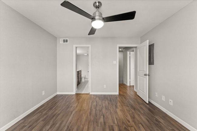 Unfurnished bedroom featuring dark wood finished floors, connected bathroom, ceiling fan, and electric panel | Image 25