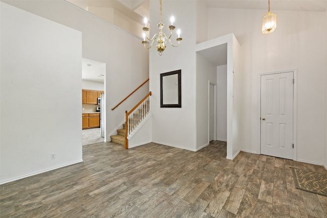 Entrance foyer with wood finished floors, baseboards, high vaulted ceiling, stairway, and a chandelier | Image 5
