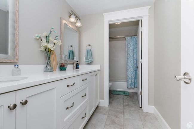 Full bath with double vanity, toilet, shower / tub combo with curtain, and a sink | Image 53