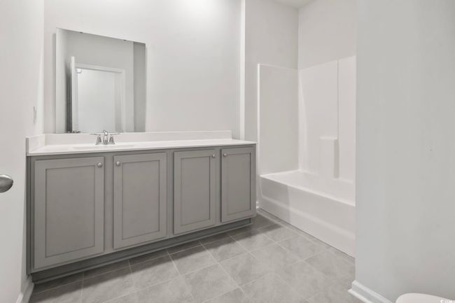 Bathroom with vanity, tile patterned floors, and washtub / shower combination | Image 26