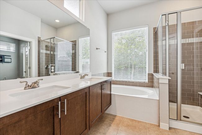 Bathroom featuring a stall shower, a bath, tile patterned flooring, and double vanity | Image 19