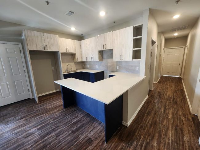 Kitchen with open shelves, baseboards, a sink, dark wood-style floors, and visible vents | Image 5