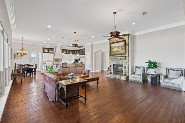 Living area with recessed lighting, arched walkways, a fireplace, and ceiling fan with notable chandelier | Image 10