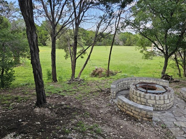 Firepit nestled among the trees behind the home and the open back yard field beyond | Image 33