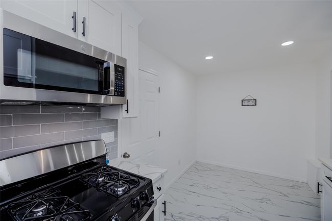 Kitchen featuring tasteful backsplash, stainless steel appliances, white cabinets, and light stone counters | Image 20