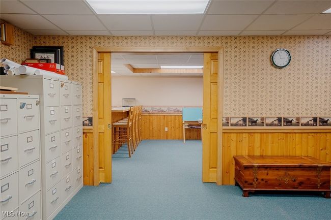 Basement featuring a paneled ceiling, wallpapered walls, a wainscoted wall, carpet, and a desk | Image 29