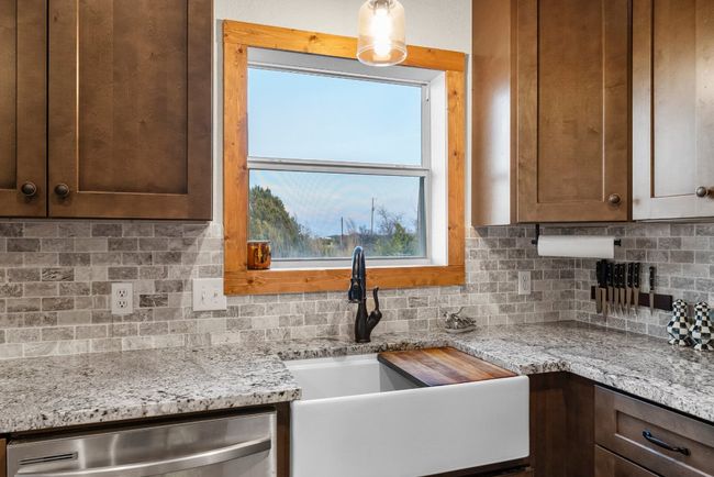 Kitchen featuring tasteful backsplash, dishwasher, a sink, and light stone countertops | Image 19