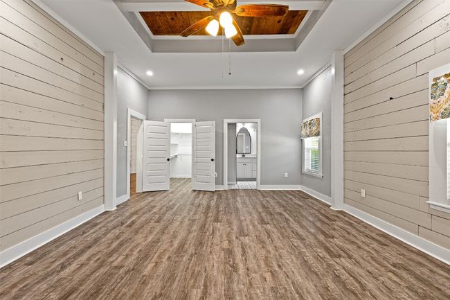 Unfurnished living room with wood finished floors, wooden walls, and a tray ceiling | Image 20