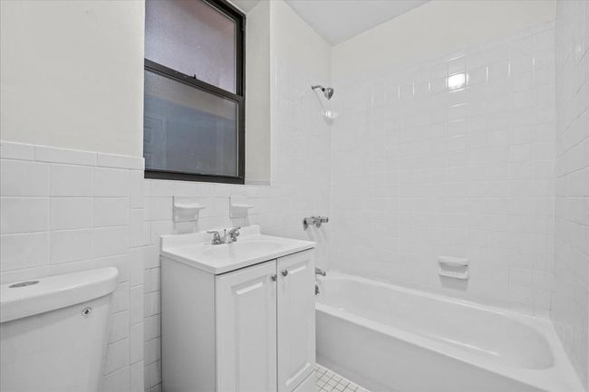 Bathroom with vanity, shower / tub combination, tile walls, and a wainscoted wall | Image 6