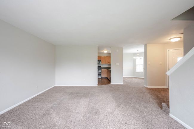 unfurnished living room featuring an inviting chandelier, baseboards, and carpet | Image 10