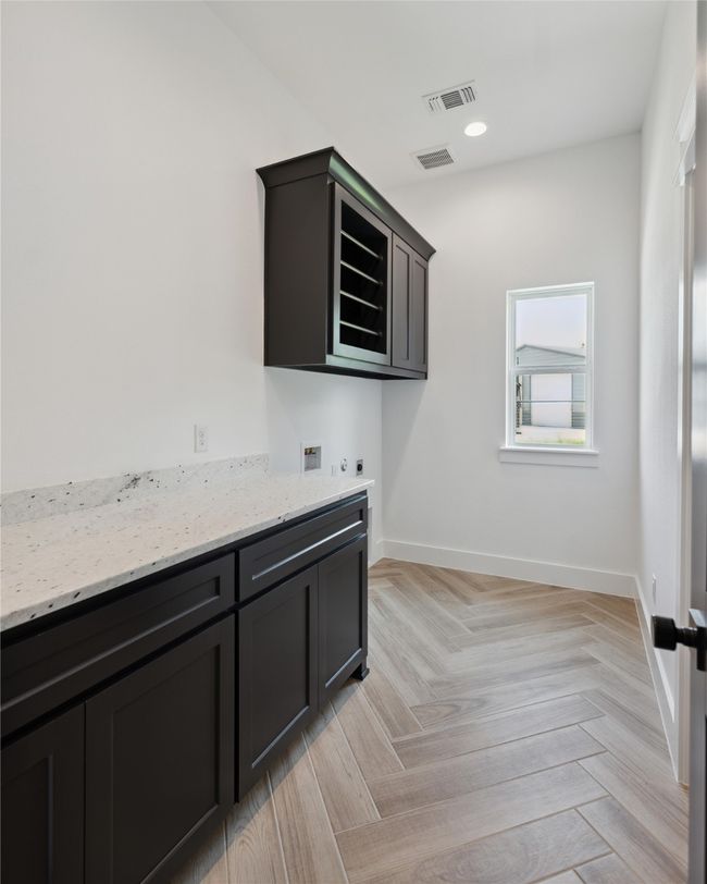 Washroom with hookup for a washing machine, cabinets, and light parquet floors | Image 28