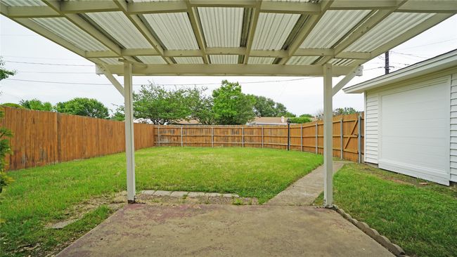 There is a lot of green space in the backyard, as seen from the covered patio. The walkway takes you to the driveway | Image 22