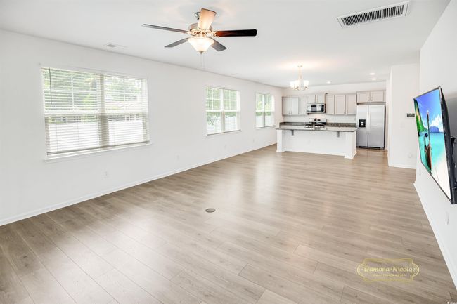 Unfurnished living room with a chandelier, ceiling fan, baseboards, light wood finished floors, and recessed lighting | Image 17