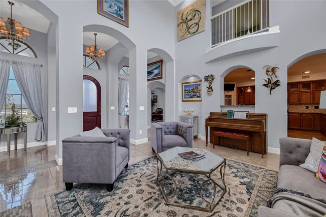 Living room featuring a towering ceiling and a notable chandelier | Image 11