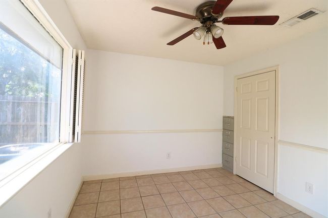 Second bedroom with large window and foldable wood shutters and ceiling fan | Image 16
