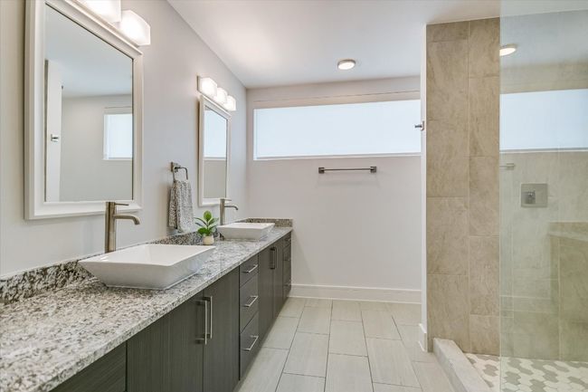 Bathroom featuring double vanity, walk in shower, baseboards, and a sink | Image 12
