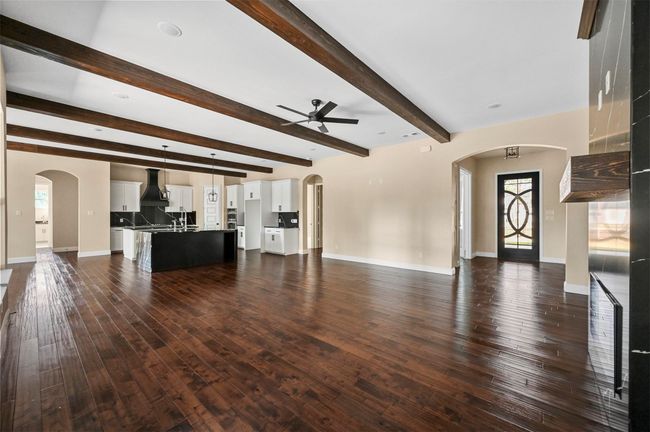 Unfurnished living room with baseboards, arched walkways, dark wood finished floors, and a ceiling fan | Image 33