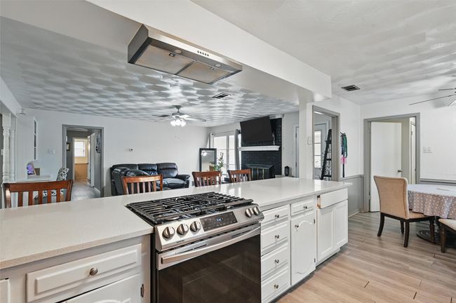 Kitchen with stainless steel gas stove, a ceiling fan, open floor plan, and light countertops | Image 5