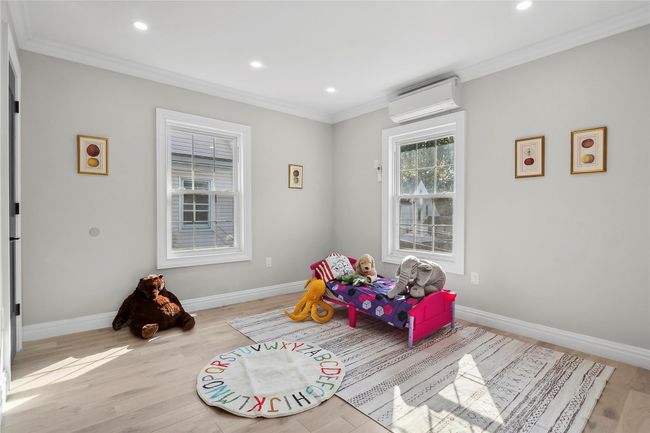 Recreation room featuring a wall mounted air conditioner, ornamental molding, recessed lighting, and light wood-style flooring | Image 6