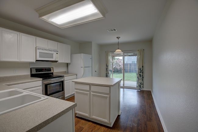 Kitchen featuring white appliances, a sink, dark wood-style floors, and white cabinetry | Image 16