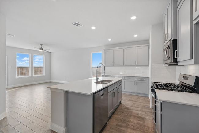 Kitchen featuring gray cabinetry, decorative backsplash, a sink, and stainless steel appliances | Image 5