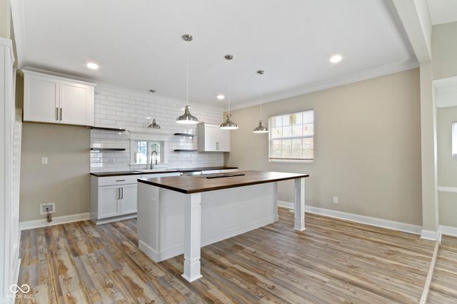 kitchen with butcher block counters, tasteful backsplash, light wood-type flooring, white cabinets, and recessed lighting | Image 13