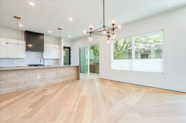 Kitchen featuring modern cabinets, white cabinetry, light countertops, decorative backsplash, and light wood finished floors | Image 7