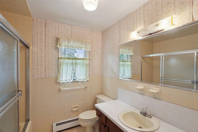 Full bath featuring wallpapered walls, a baseboard heating unit, vanity, a wainscoted wall, and toilet | Image 26