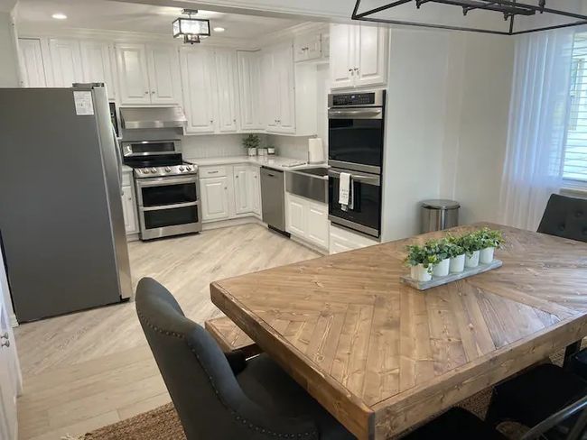Kitchen featuring appliances with stainless steel finishes, light wood-type flooring, and white cabinetry | Image 8
