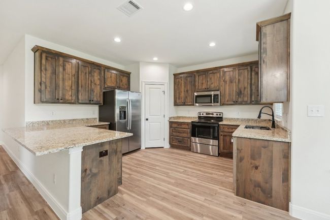 Kitchen with a peninsula, Vinyl Wood Plank floor, appliances with stainless steel finishes, and a sink | Image 18