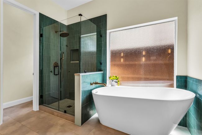 Bathroom featuring tile patterned floors, a soaking tub, a shower stall, and tile walls | Image 19