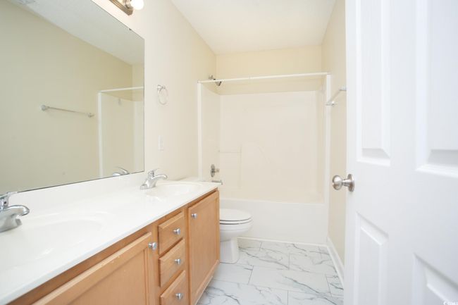 Full bath featuring toilet, marble finish floors, double vanity, bathing tub / shower combination, and baseboards | Image 28