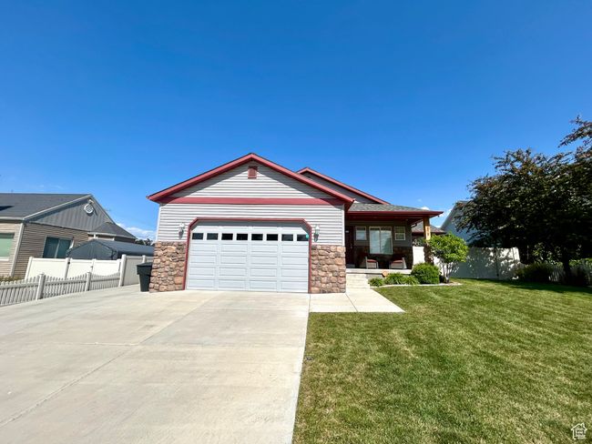 Single story home with driveway, stone siding, an attached garage, and a porch | Image 5