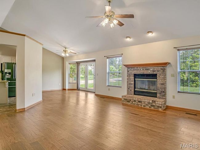 Living room with vault ceiling, ceiling fan, a fireplace, and wood finished floors | Image 7