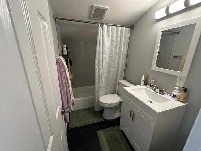 Bathroom featuring tile patterned floors, vanity, visible vents, toilet, and shower / bath combo with shower curtain | Image 4