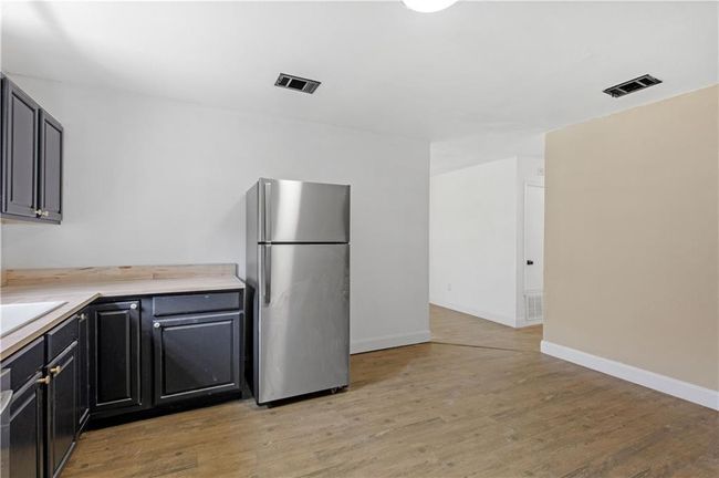 Kitchen featuring light countertops, light wood-style floors, visible vents, and freestanding refrigerator | Image 8