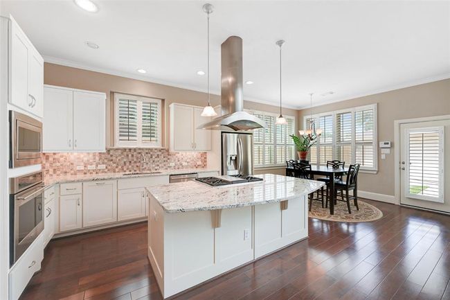 Custom cabinetry, double ovens, mosaic tile backsplash, and stainless steel appliances complete this stylish and functional space. | Image 11